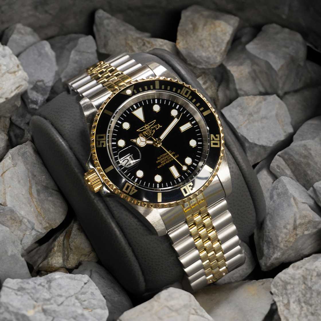 Image of a silver wristwatch with golden details, with a black clock face and white hour markers.