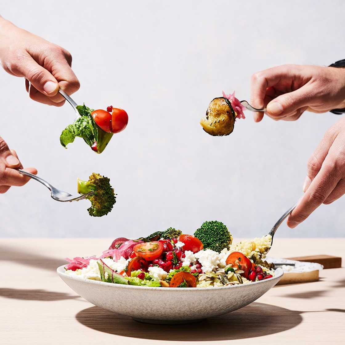 4 people with a fork digging into a salad bowl