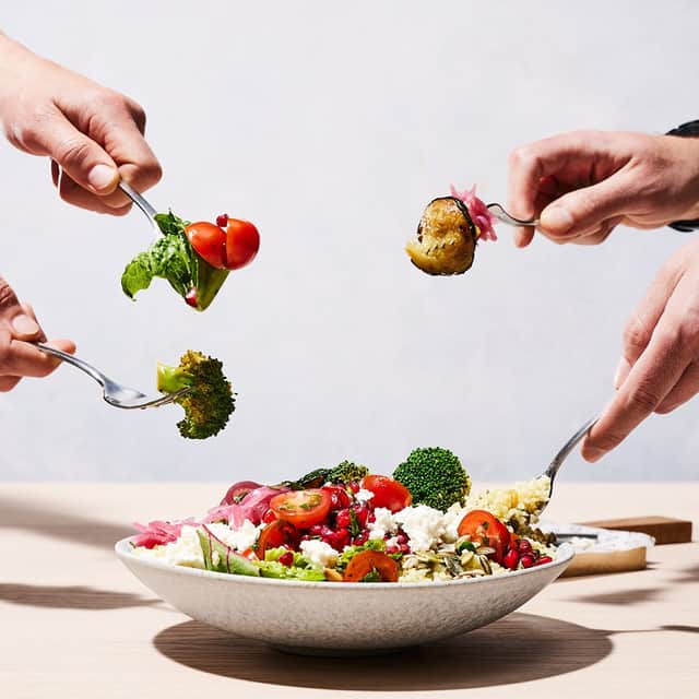 4 people with a fork digging into a salad bowl