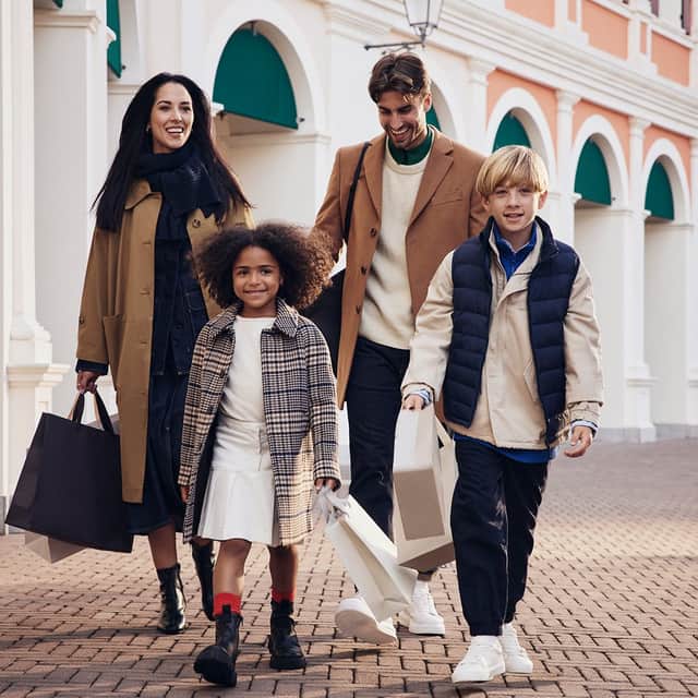 A happy family walking with shopping bags and their dog