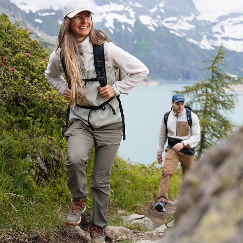 Columbia Two people hiking by a mountain lake.