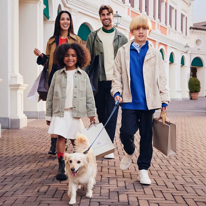 A happy family walking with shopping bags and their dog.