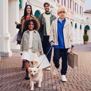 A happy family walking with shopping bags and their dog.